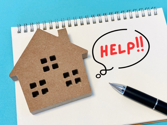 住宅の模型から吹き出しでHELP!と書かれている写真。